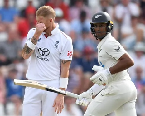 Ben Stokes wipes his face as Rachin Ravindra runs past him while holding his bat in his right hand