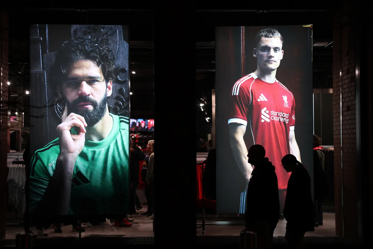 Large display screens featuring Liverpool FC players Alisson Becker and Harvey Elliott in a retail store window.